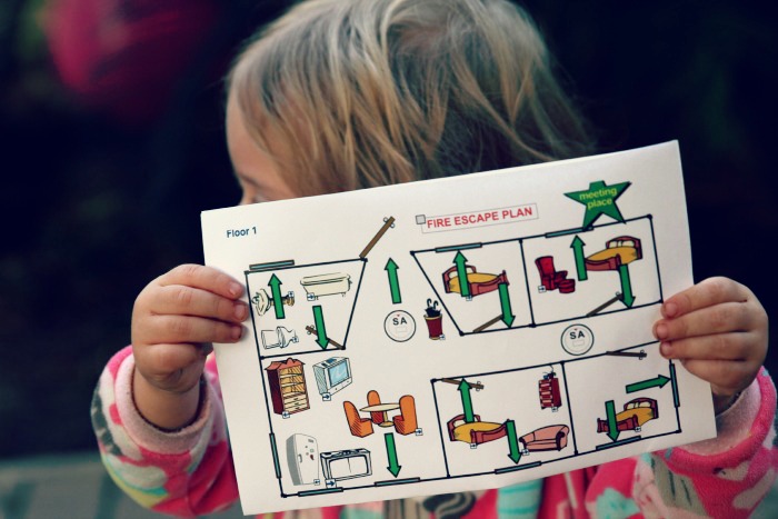 Child holding a fire escape plan for home safety.