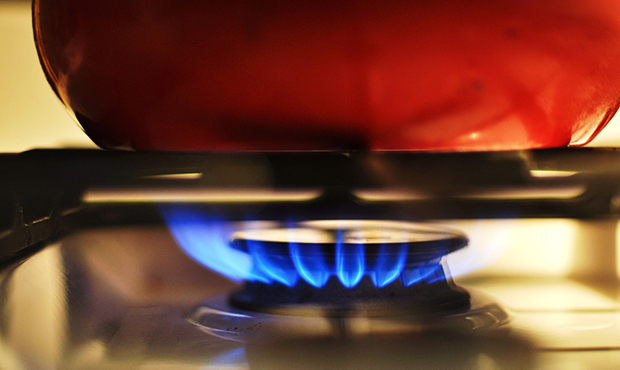 Cooking pot on a stove with an active flame.